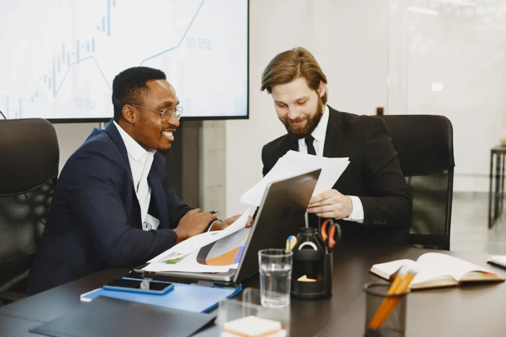 como-vender-pela-internet-sem-ter-loja-virtual dois homens sorrindo com papéis em um escritório