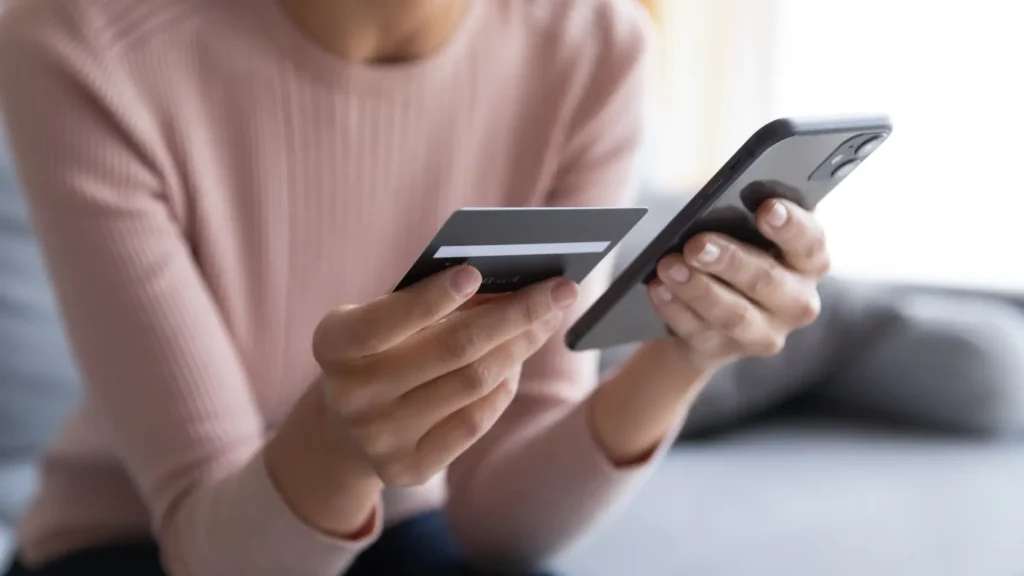 pci compliance - mãos segurando celular e cartão de crédito