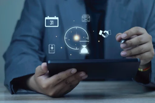 gestao-de-tempo-e-produtividade Empresário usando tablet com ícones de holograma de gerenciamento de tempo: relógio, calendário e aperto de mão. Conceito de eficiência, cumprimento de prazos e planejamento de fluxo de trabalho.