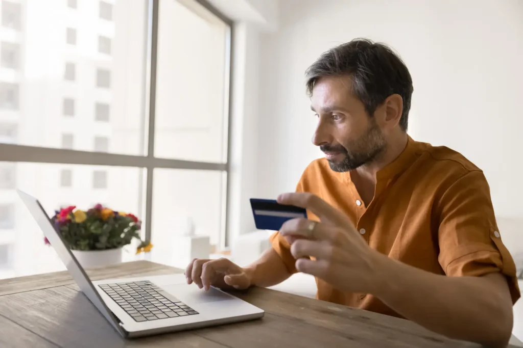 chargeback - Gestão financeira à distância. Homem maduro empresário sentado na mesa comprar mercadorias do site de comércio eletrônico fazer a revisão de pagamento de negócios finanças transferências de conta bancária usando cartão de crédito notebook em casa escritório