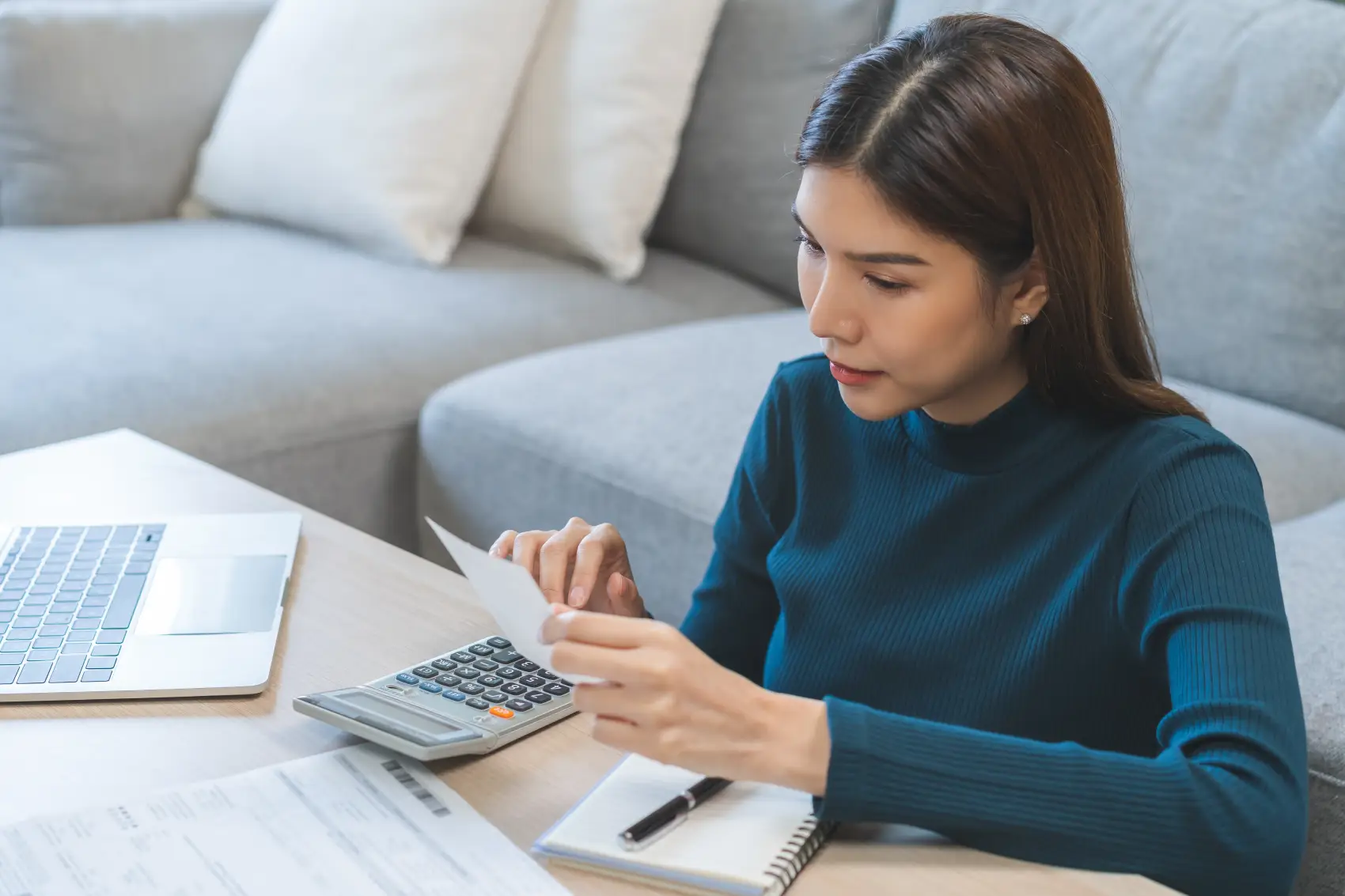 como começar a investir - mulher asiática usando calculadora para calcular as despesas mensais