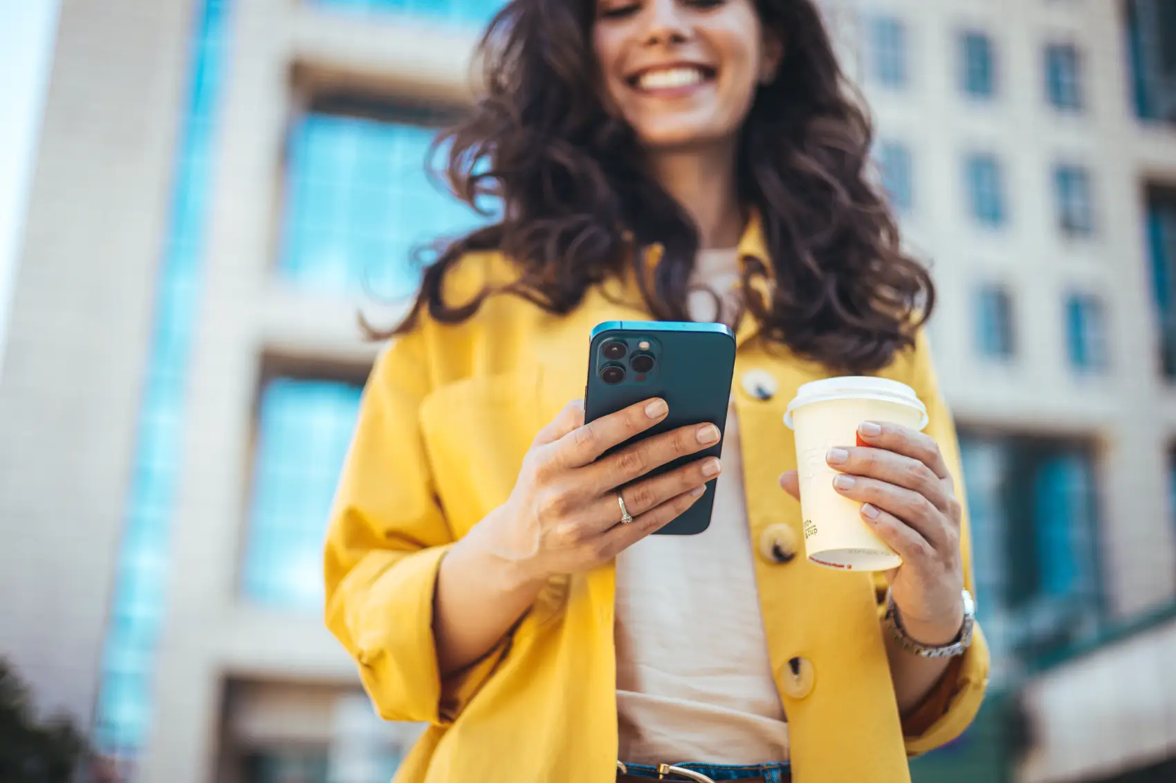 o que é conta digital - Jovem empresária de atitude positiva, com um copo de café para viagem na mão, usando o celular