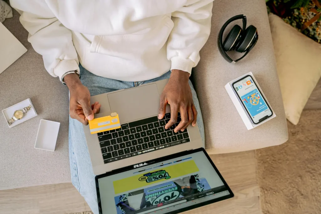 cupom-loja-online homem olhando cartão e com notebook no colo definindo sua compra online