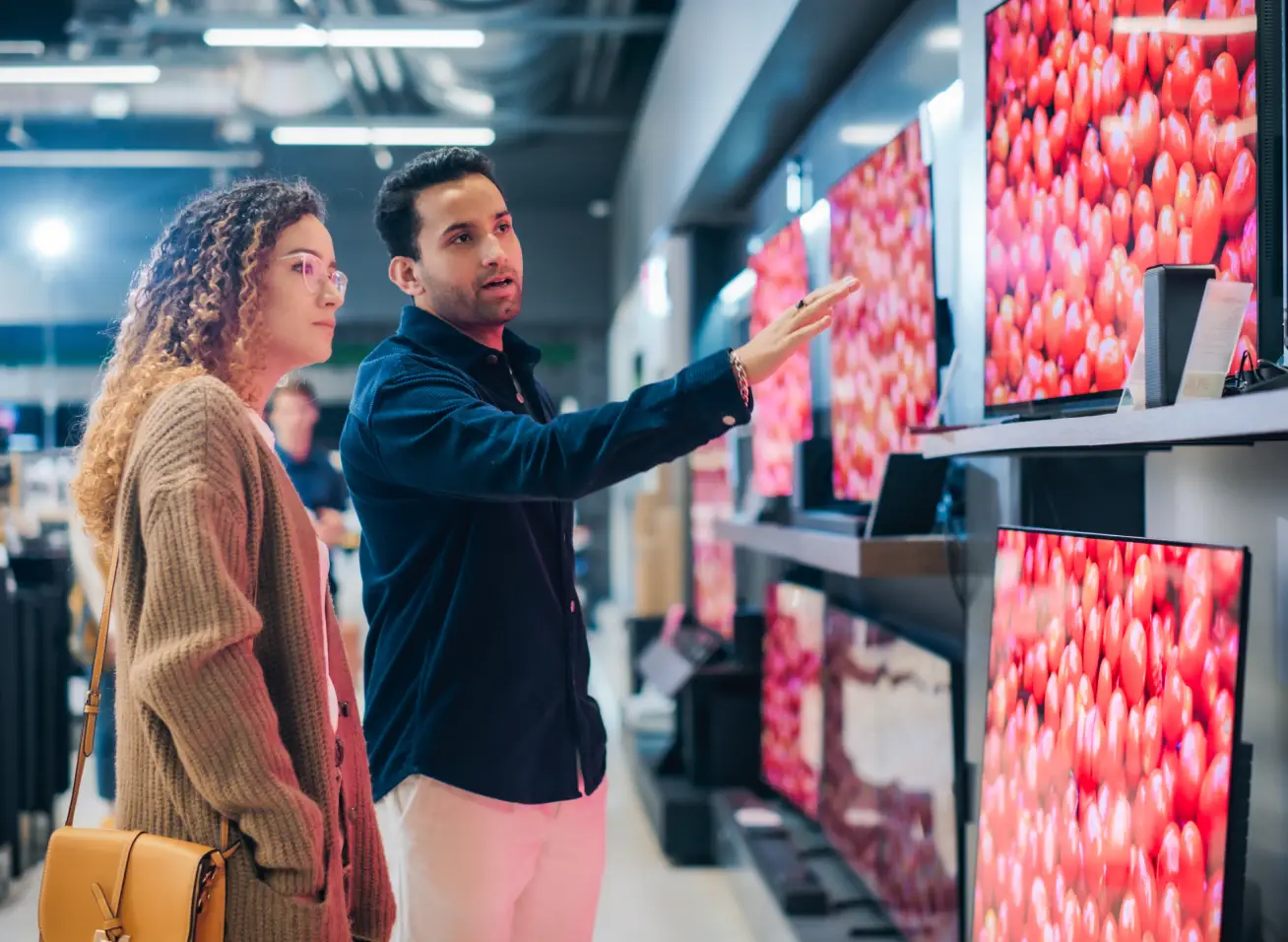o que comprar na black fridayvvvvvvv - homem e mulher observam televisões em uma loja