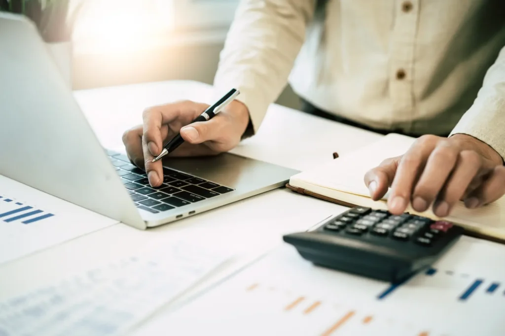 darf imposto de renda - mão usando calculadora para calcular o saldo de dinheiro da conta e renda
