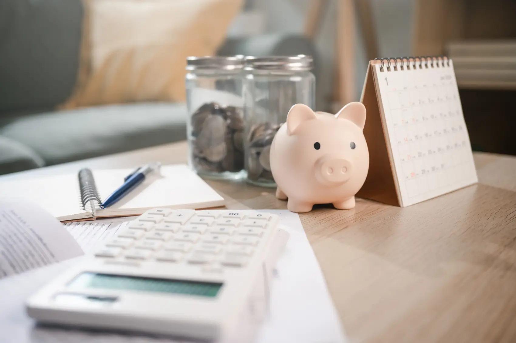 calendário econômico - Um cofrinho de porquinho sobre uma mesa perto de uma calculadora e um calendário