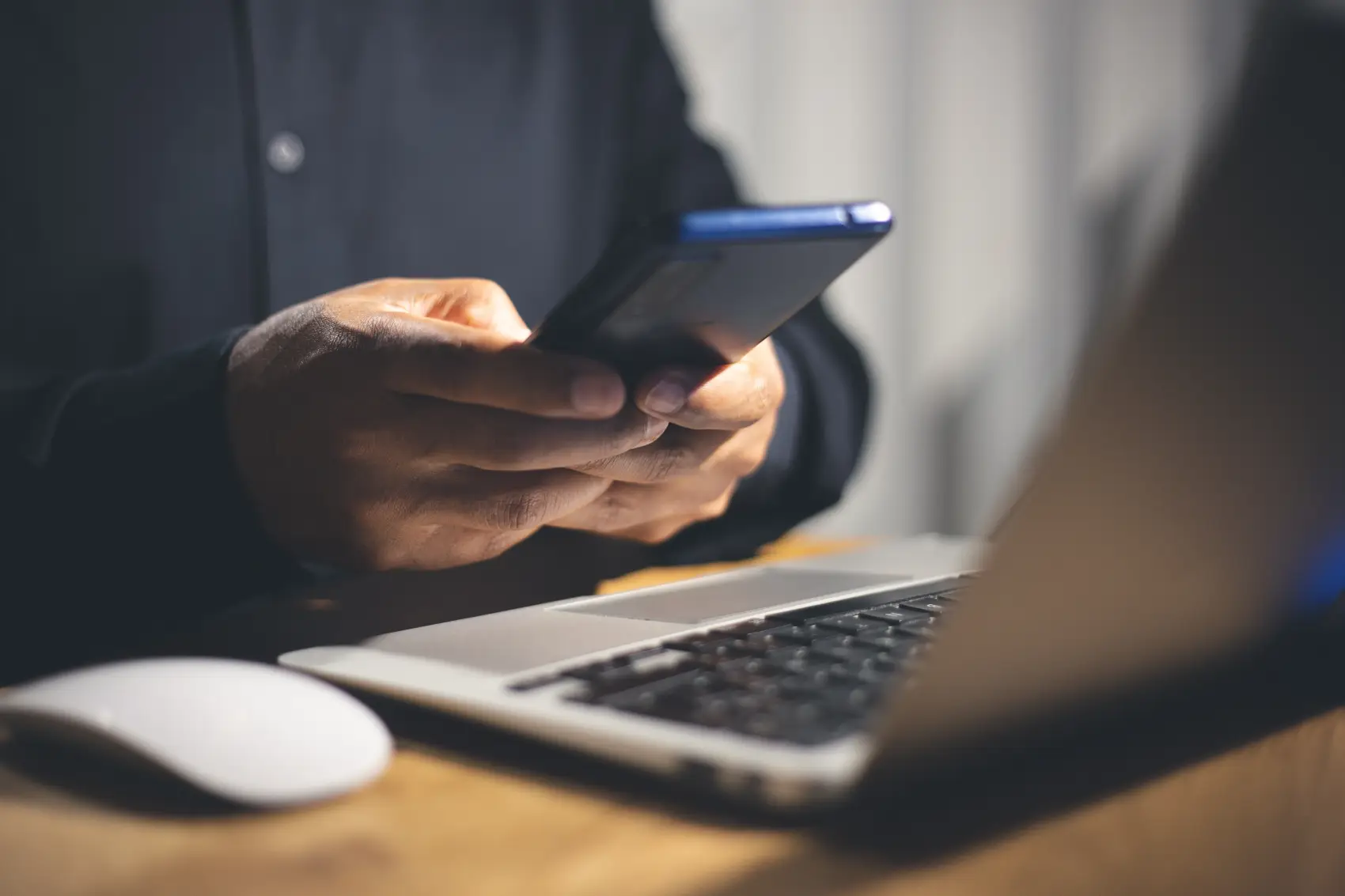 como apagar extrato do pix - mãos segurando celular próximo a um notebook e um mouse