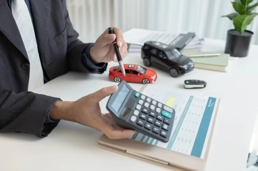 como-pagar-licenciamento-atrasado Um funcionário está fornecendo informações de carro. com miniatura de brinquedo, calculadora e chave do carro