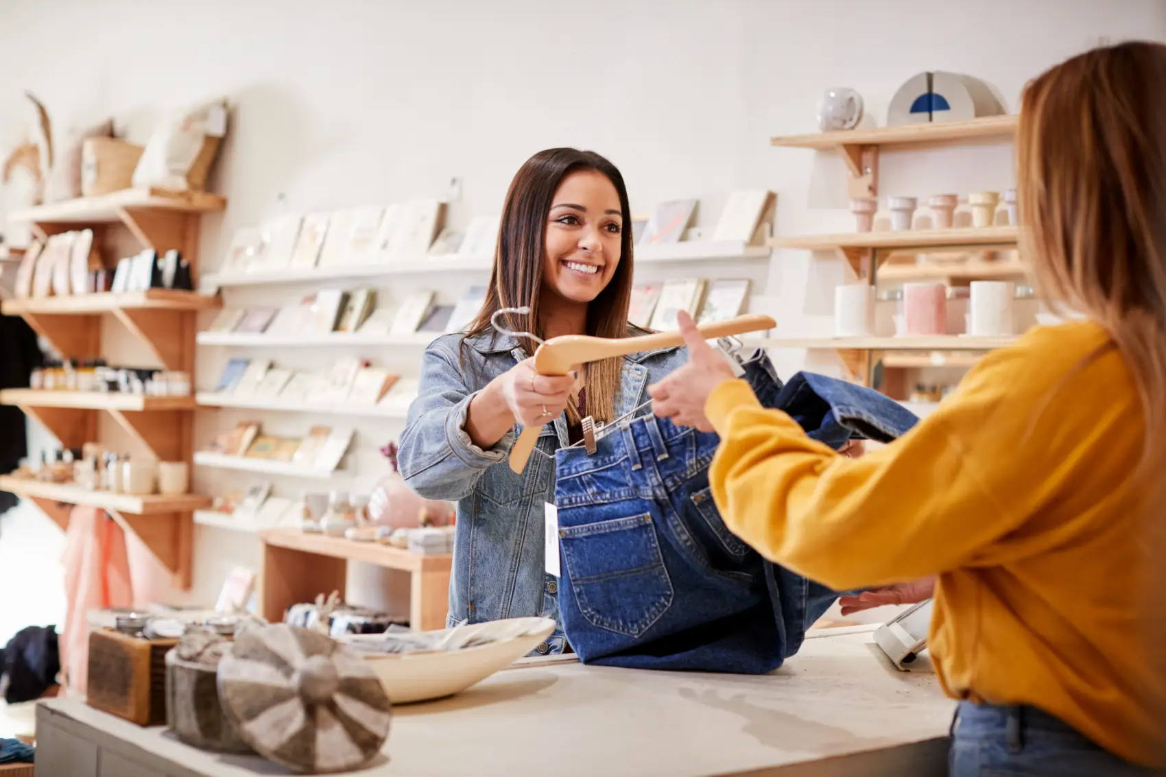 dia do comerciante - mulher feliz entregando calça jeans para cliente