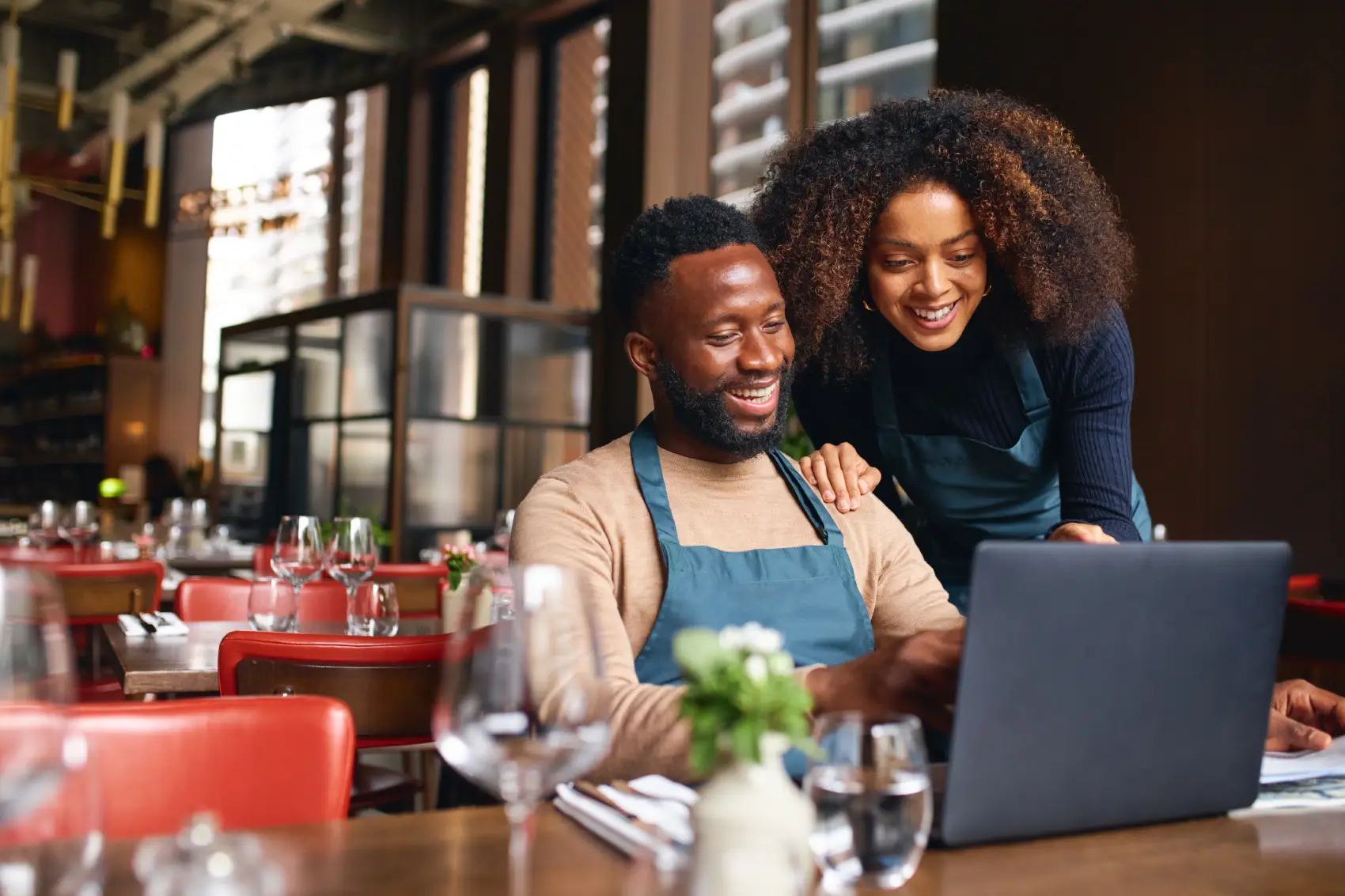 melhor conta pj - casal negro dono de restaurante sentado no estabelecimento em frente ao computador