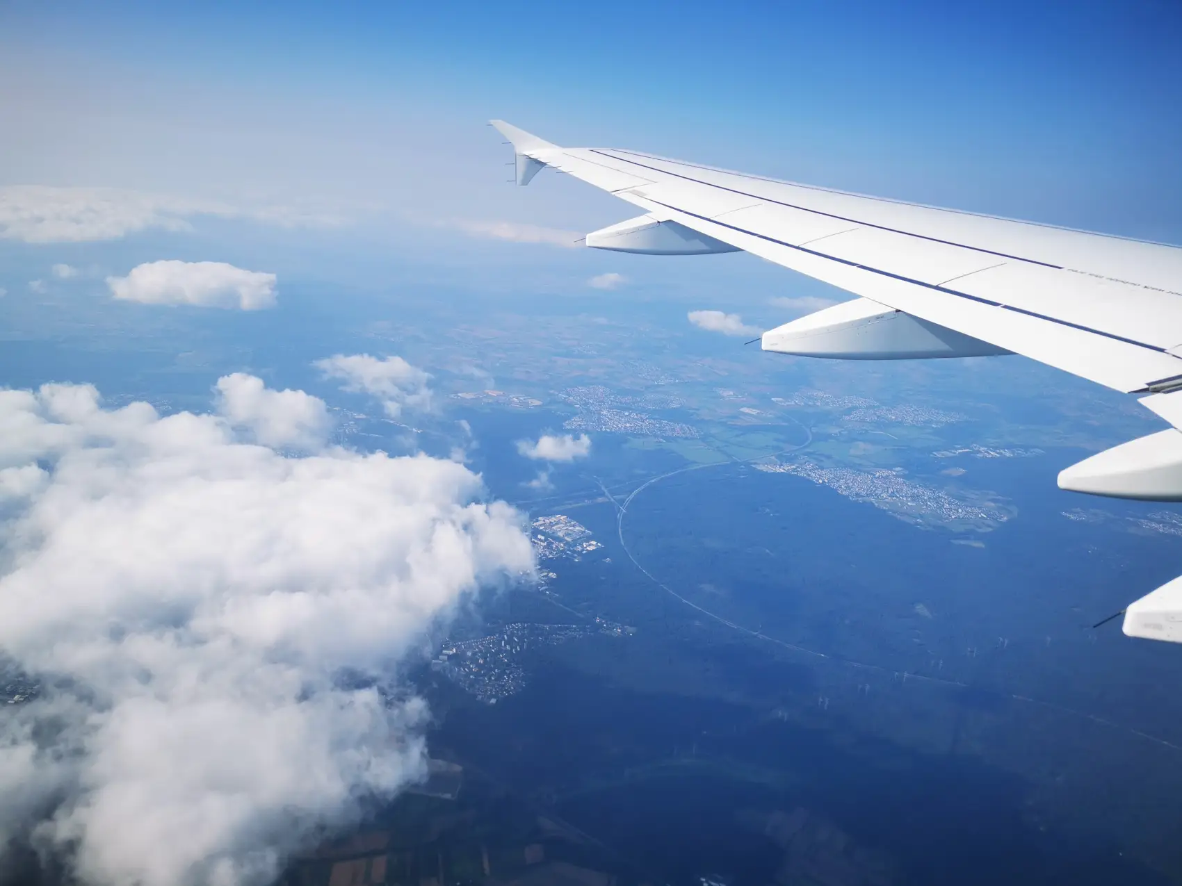 como comprar passagem aérea barata - A asa de um avião de passageiros durante o voo contra um céu azul com nuvens