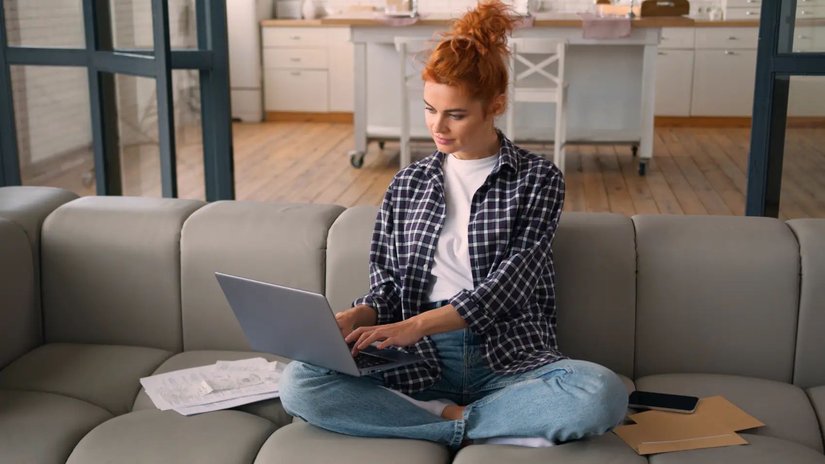o que é amortização de empréstimo - Mulher caucasiana sentada no sofá de casa usando laptop