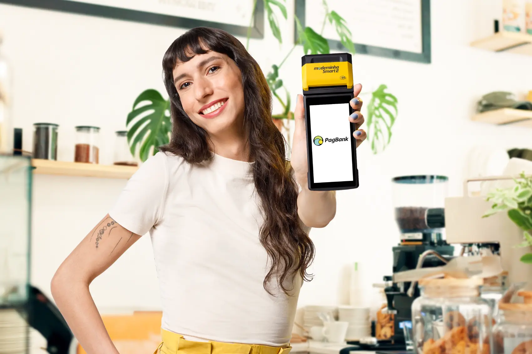 trocar maquininha pagbank - mulher caucasiana segurando maquininha pagbank Smart 2 sorrindo, olhando para a câmera