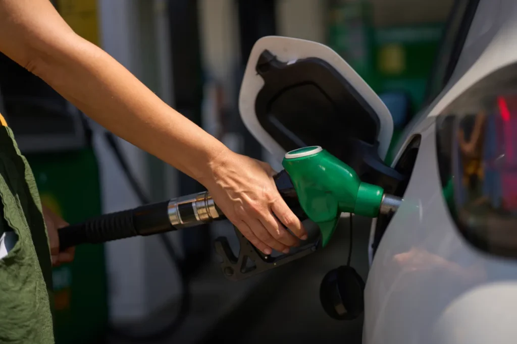 álcool ou gasolina - Mulher reabastecendo carro em posto de gasolina, segurando bocal da bomba de combustível verde