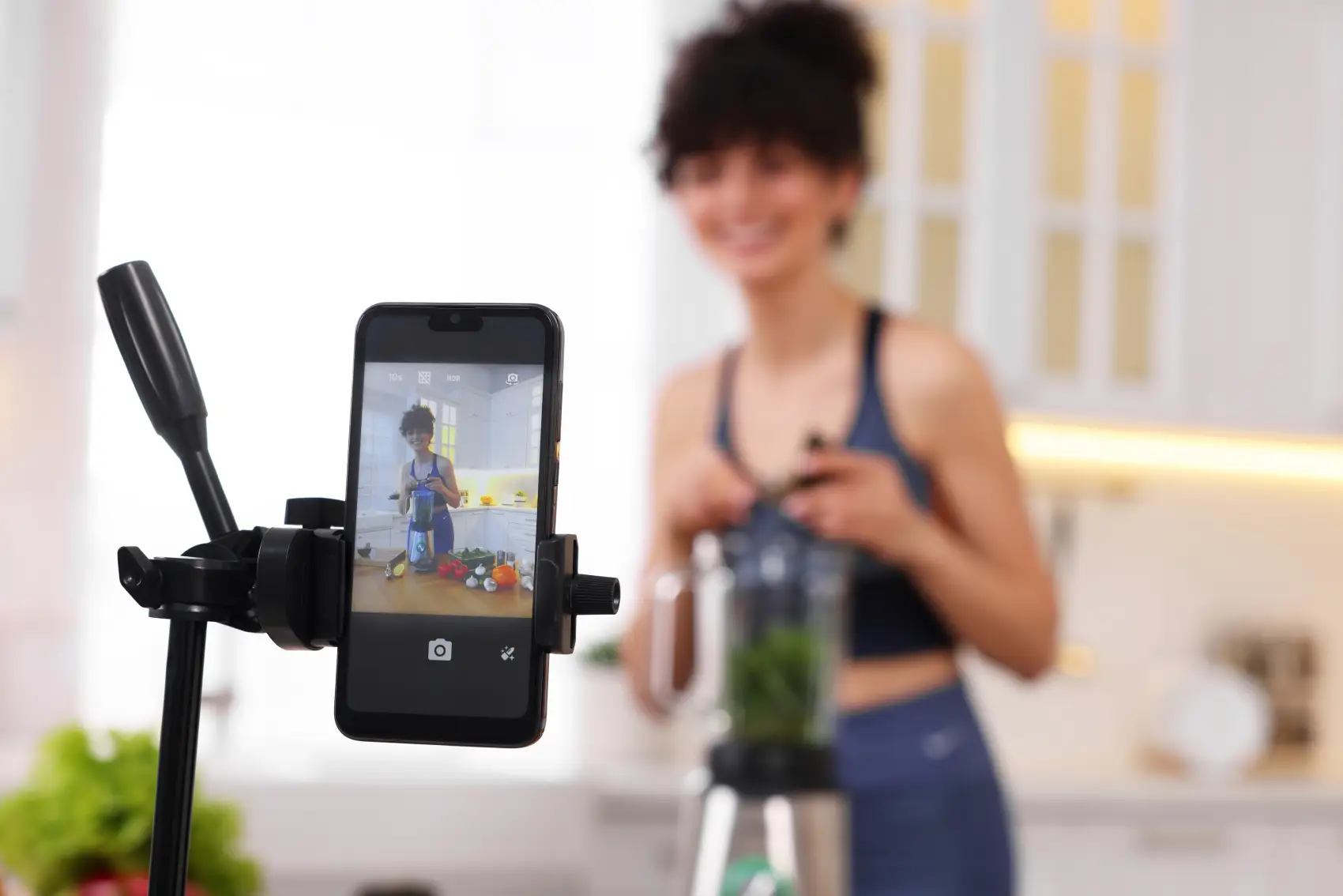 como ganhar dinheiro no tiktok - Blogueira de culinária gravando vídeo na cozinha, com foco no smartphone.