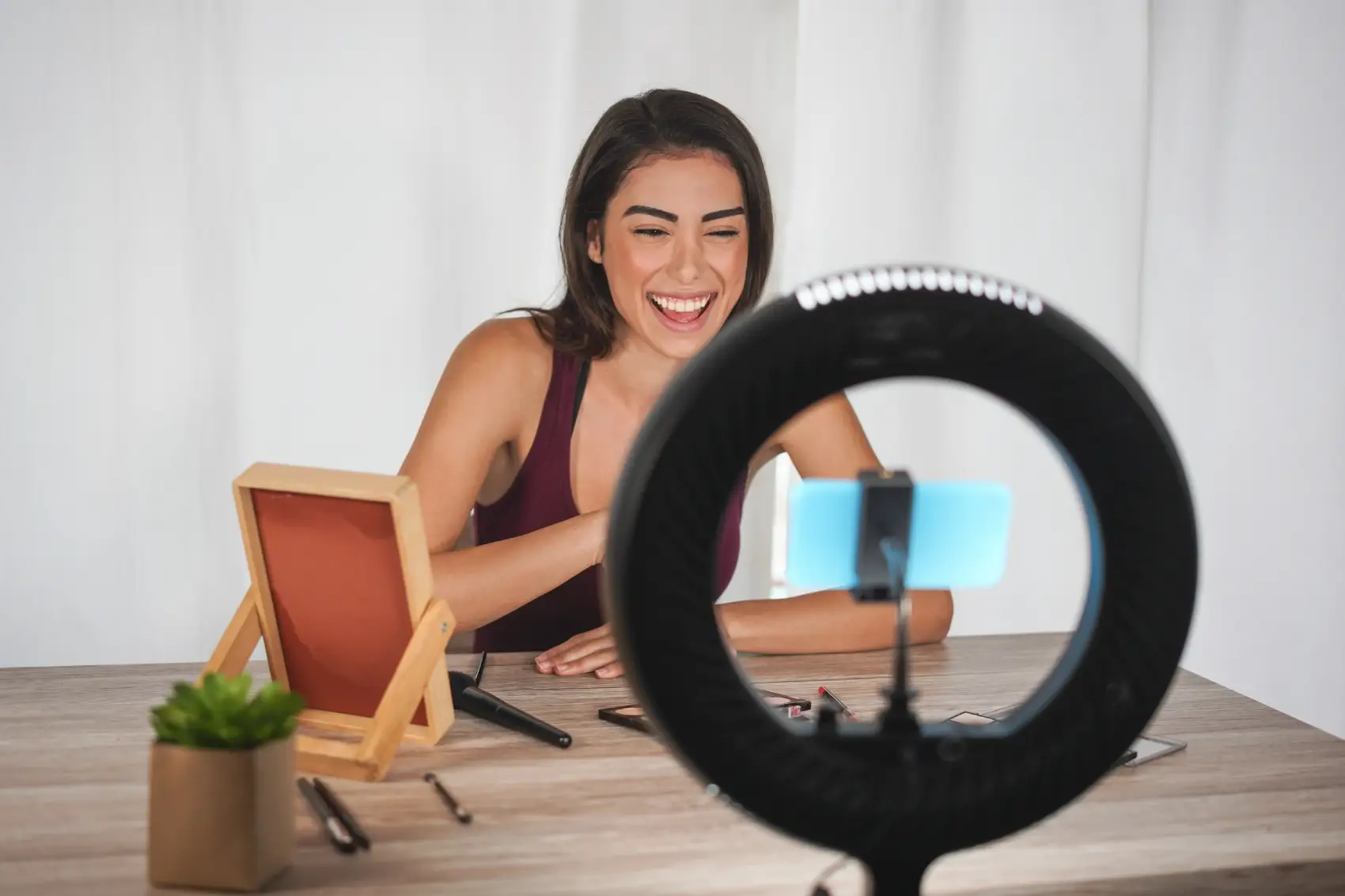 como ganhar dinheiro no youtube​ - Mulher jovem influenciadora criando vídeos de mídia social com câmera de smartphone enquanto coloca maquiagem