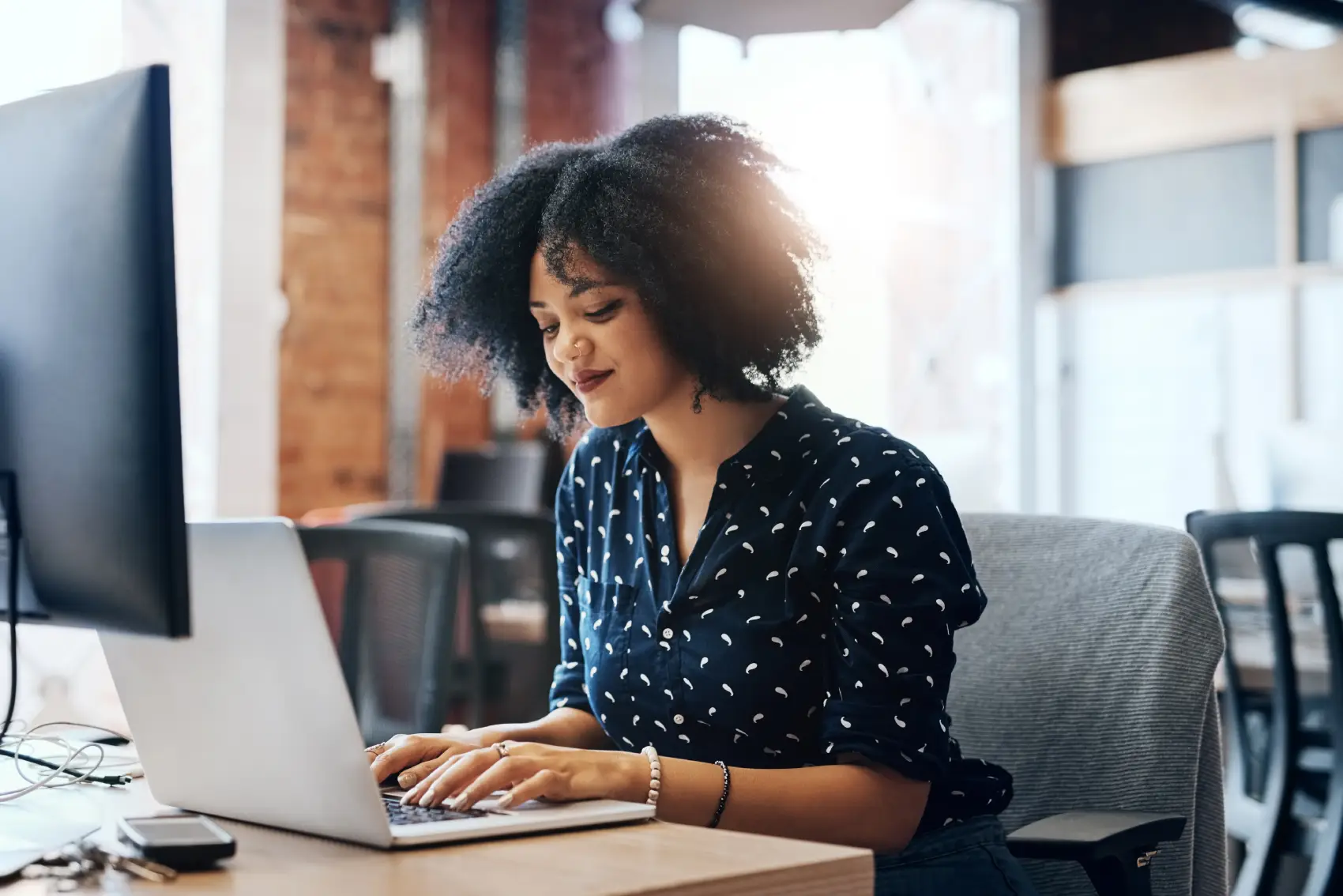 desktop seguro - mulher negra digitando e sorrindo para o laptop no escritório