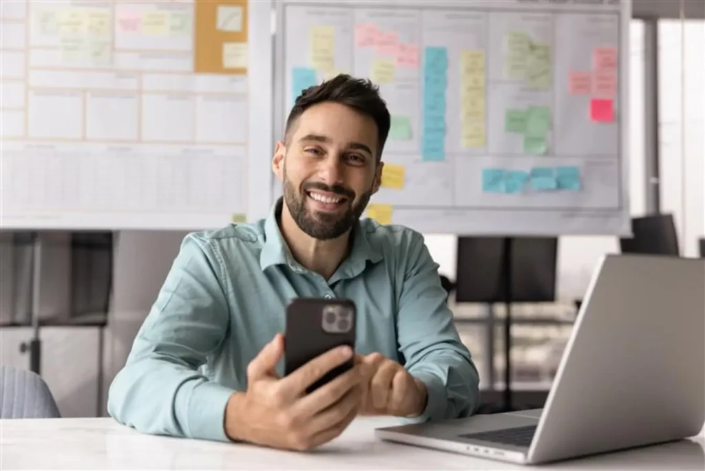Renegociação de Dívidas - homem branco sorrindo com um celular na mão