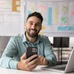 Renegociação de Dívidas - homem branco sorrindo com um celular na mão
