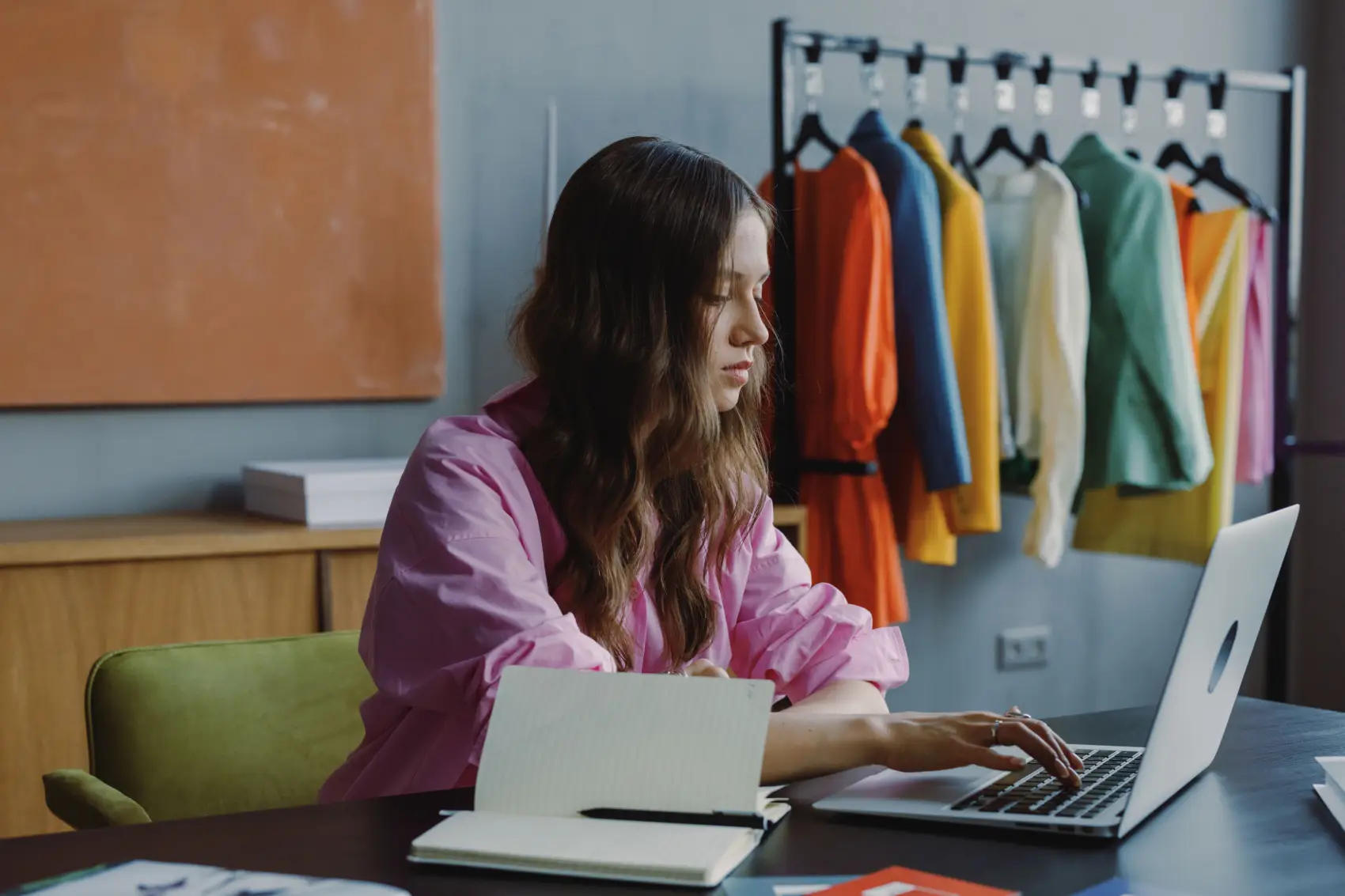 quem-pode-ser-mei mulher em mesa de escritório com roupas coloridas em cabide
