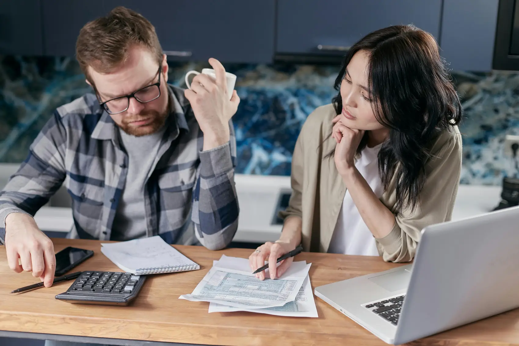 como-declarar-heranca-no-imposto-de-renda casal fazendo cálculos com calculadora notebook e papéis na mesa