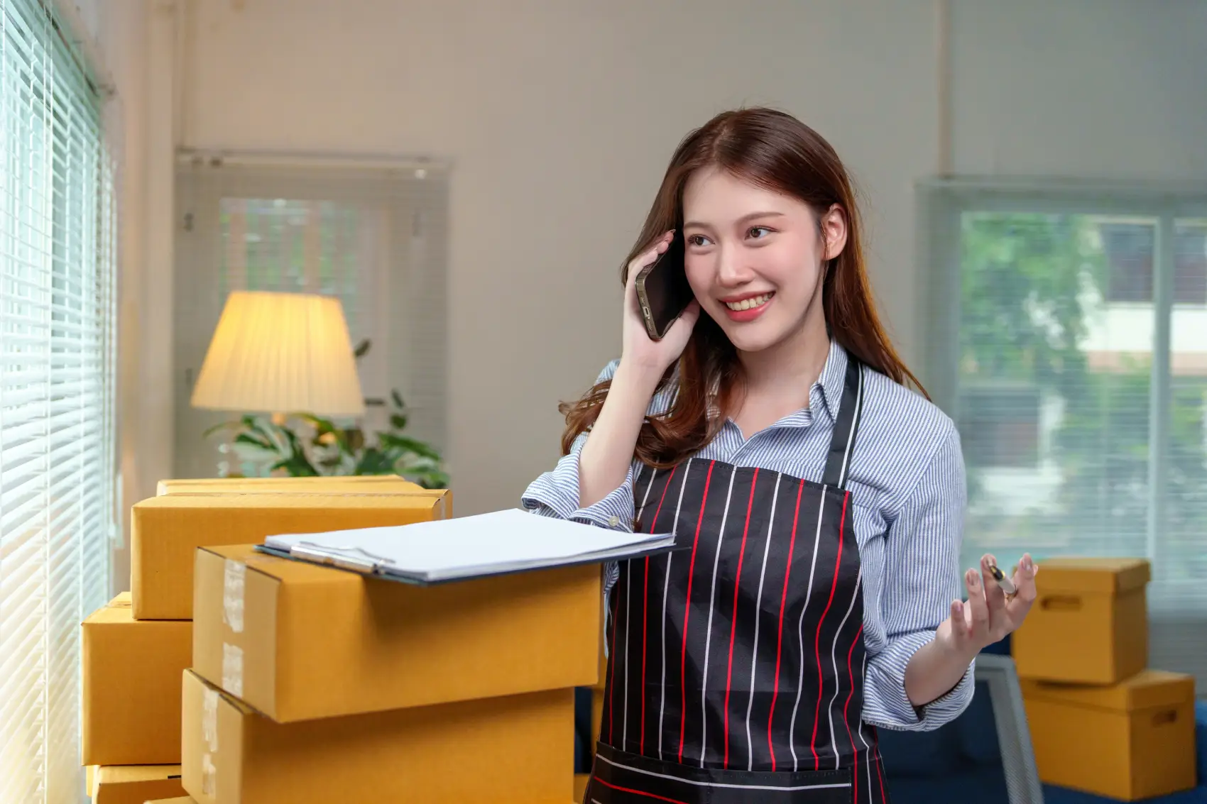 dia mundial da internet​ - Mulher feliz empresária recebendo pedidos de clientes via telefone, preparando caixas de papelão para envio de sua loja de escritório em casa