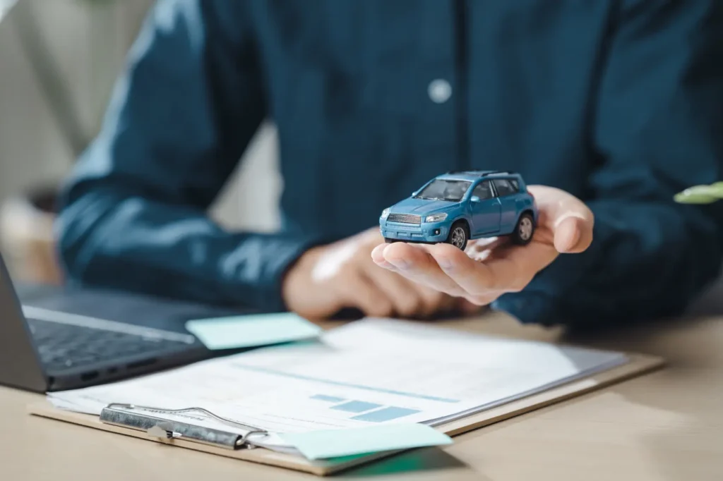 carro elétrico paga ipva​ - Um homem está segurando um carro de brinquedo em sua mão