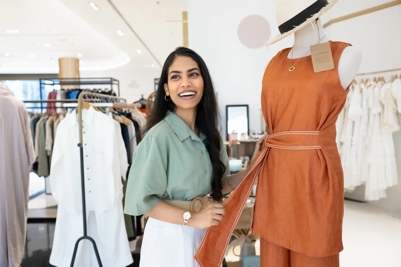 como abrir uma loja de roupas - Jovem gerente de loja alegre ajustando roupas em manequins