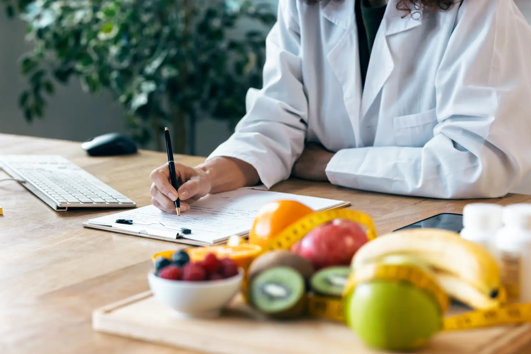 CNPJ para nutricionista - Close-up da nutricionista escrevendo algumas notas enquanto trabalha com computador na consulta
