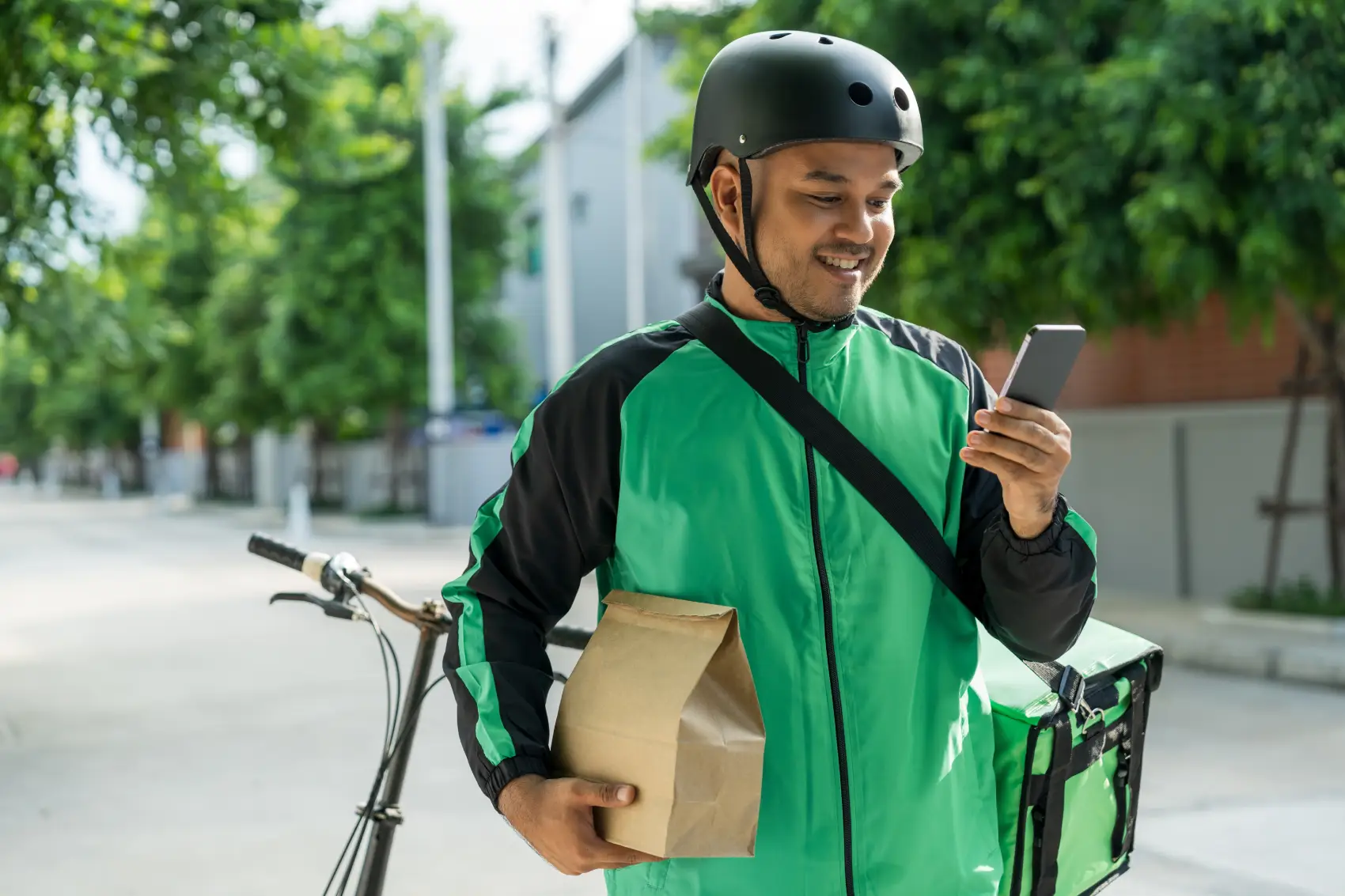 quanto ganha um entregador​ - Entregador de comida de uniforme verde e capacete, pedalando uma bicicleta para realizar uma entrega ao cliente
